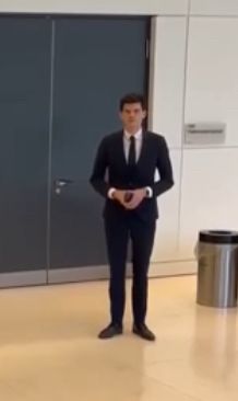 Ein Mann steht im Hintergrund der FDP Pressekonferenz und formt mit seinen Händen eine Raute.