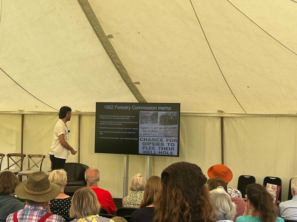 John Henry Philips giving a talk in a large tent - screen behind him and audience in front. 
