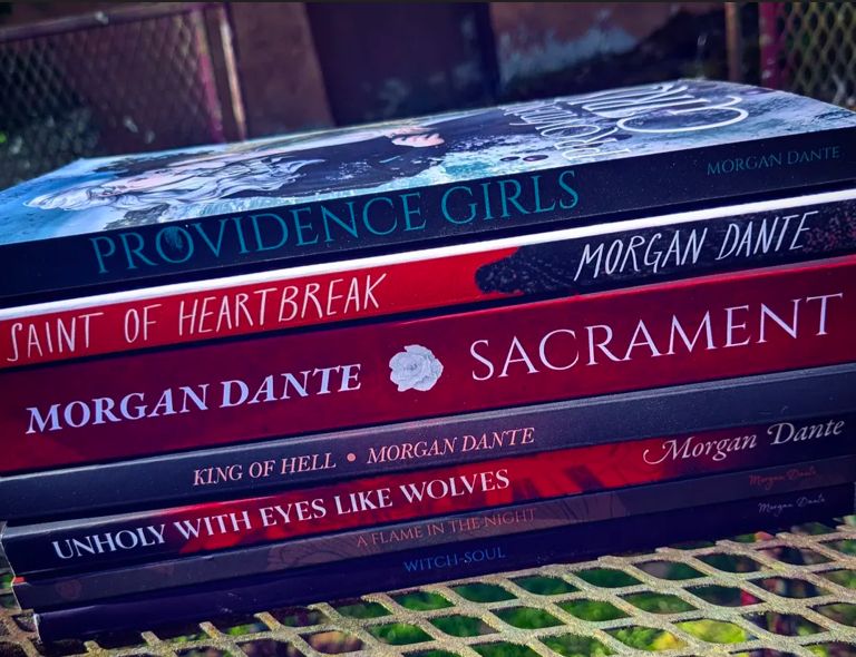 A stack of books that I wrote. From top to bottom: Providence Girls, The Saint of Heartbreak, Sacrament, King of Hell, Unholy With Eyes Like Wolves, A Flame in the Night, and Witch Soul.