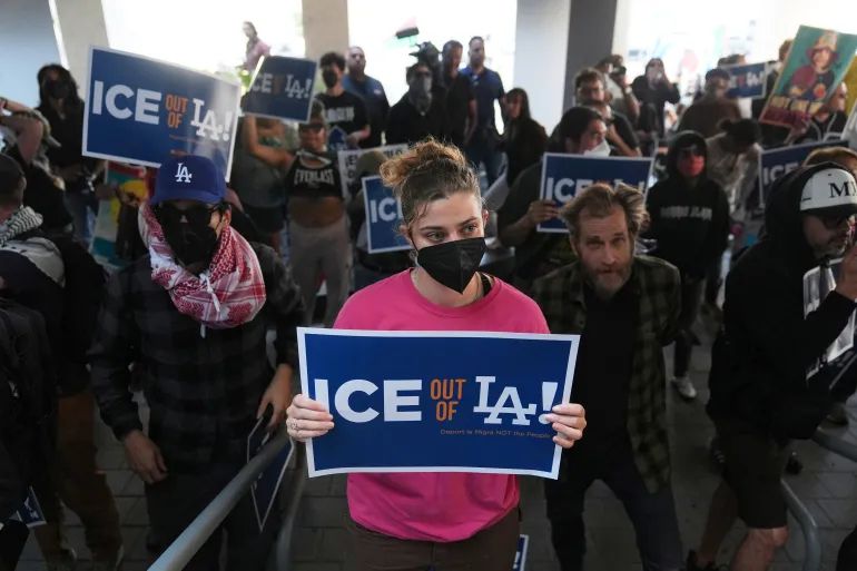 Protestors holding signs that say "Ice out of LA"