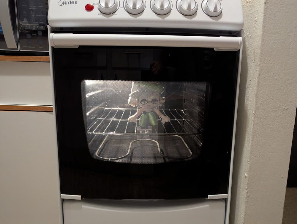 Marie Plush sits inside an oven. The backlight is on so you can see her through the glass door.