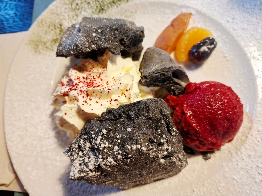 Buntes Dessert mit schwarzer Merengue und Zwetschgensorbet.