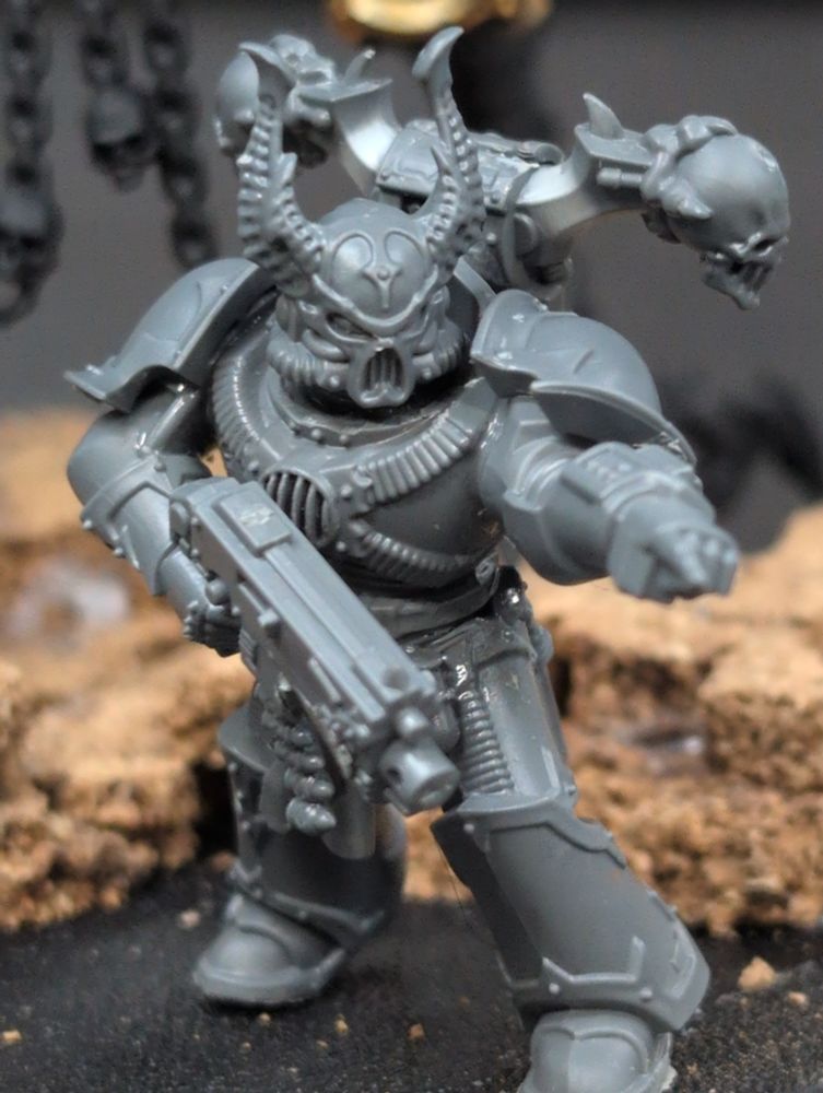 Unpainted Chaos Space marine cradling it's weapon in its right hand and pointing with its left
