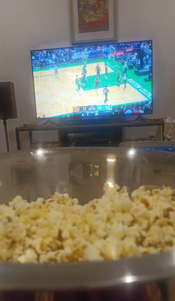 a bowl of popcorn in front of a TV showing the knicks-celtics game.