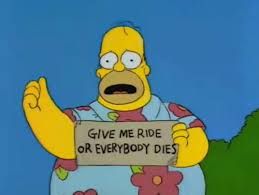 Homer Simpson in a muumuu holding a sign saying "GIVE ME RIDE OR EVERYBODY DIES"