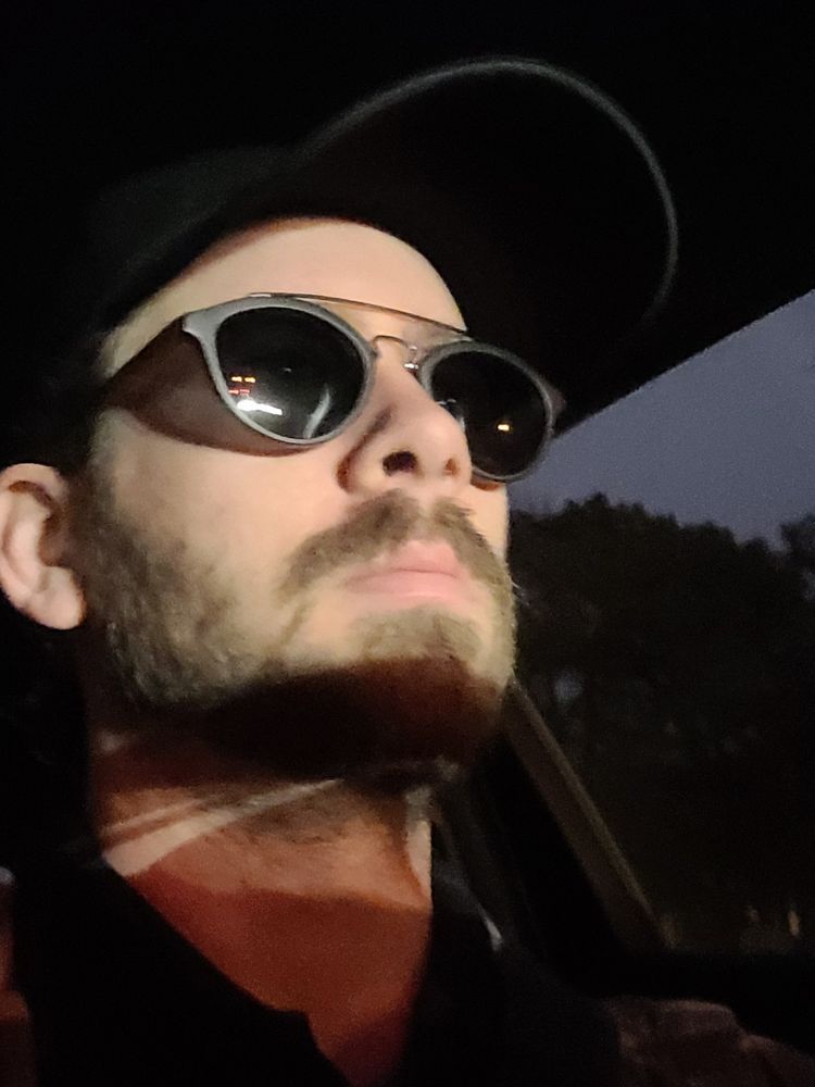 Photographer with sunglasses on with the other car's headlights clearly visible on his face, at 0630 in the morning