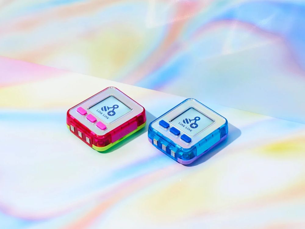 A clean promotional shot of two SEGA Emojam pagers, one in red/white shell and one in blue/white shell.
