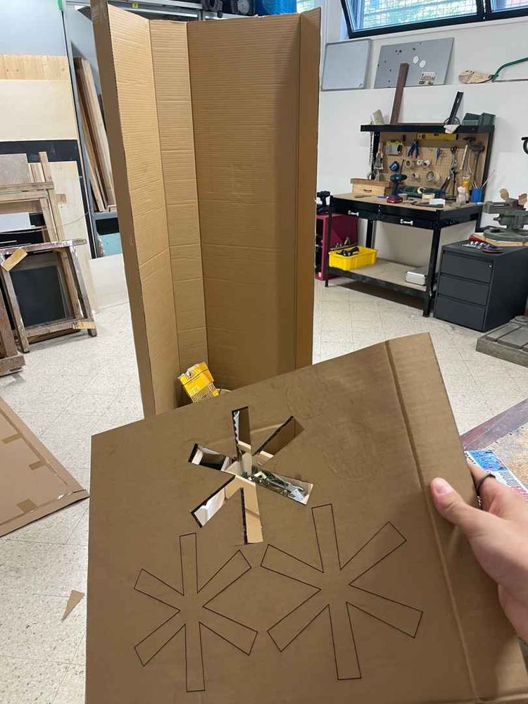 The Fediverse symbol engraved in a cardboard stencil, and a human-size cardboard construction on the background.