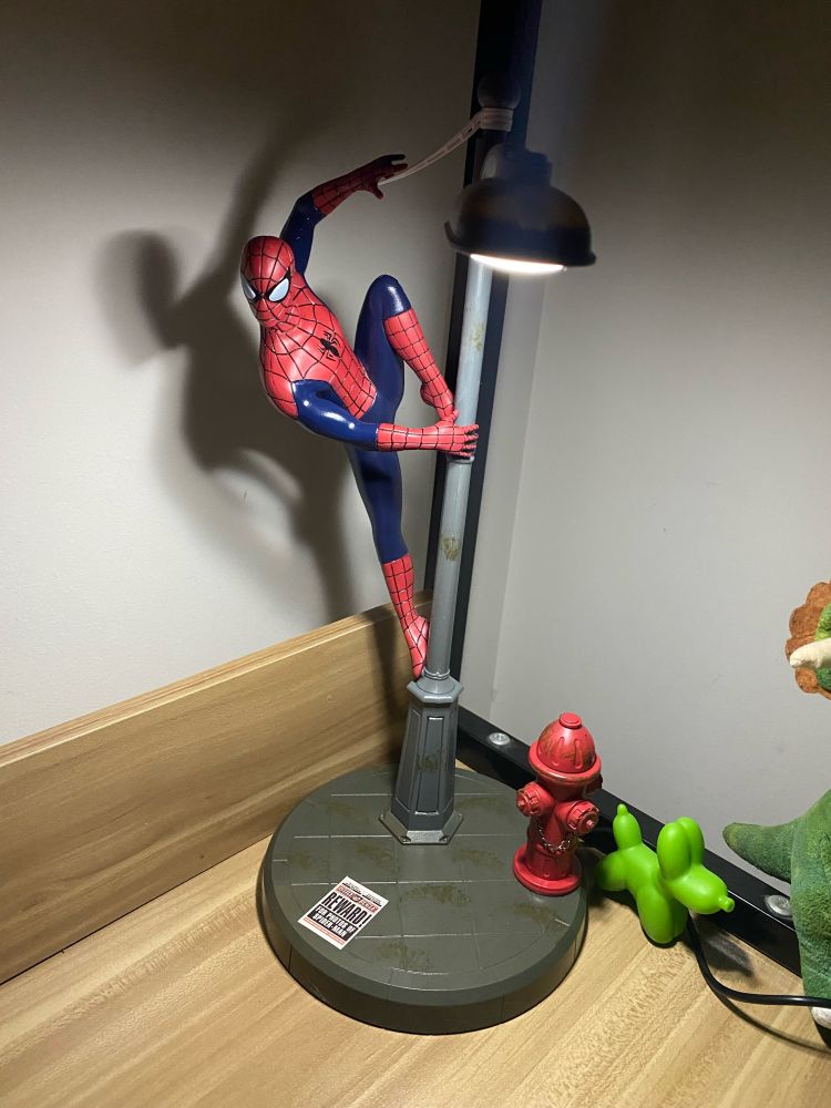 Spiderman desk lamp. The lamp is a street pole that spider man is hanging off onto 