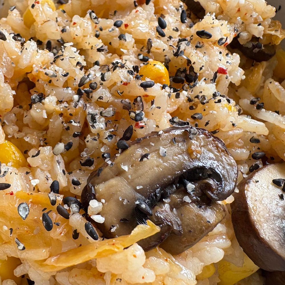 Rice, mushrooms, sweetcorn, and pieces of kimchi, with cracked black sesame seeds