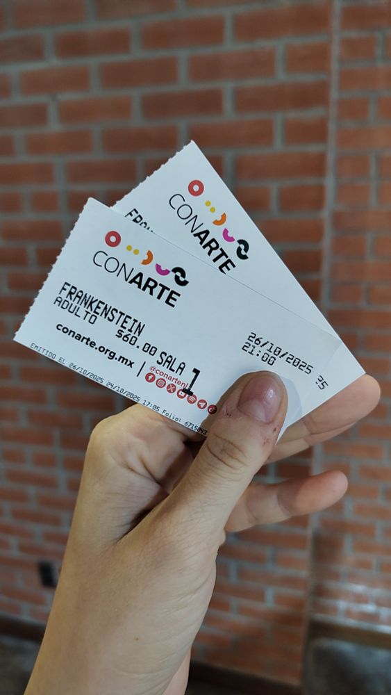 una mano blanca y descuidada sostiene dos boletos de la cineteca nuevo león para FRANKENSTEIN (2025, dir. Guillermo del Toro), con fecha para el 26 de octubre. la pared del fondo es de ladrillo rojo 