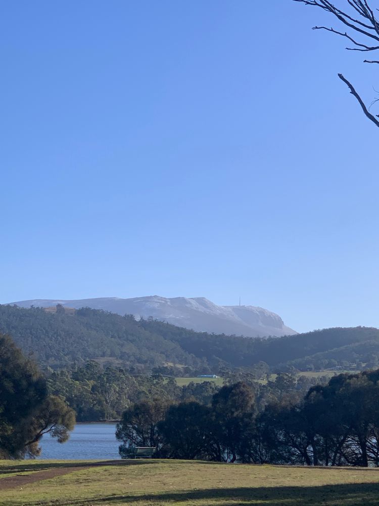 View over a bay and low hills to the dolerite (organ pipes) of a majestic mountain against a blue sky