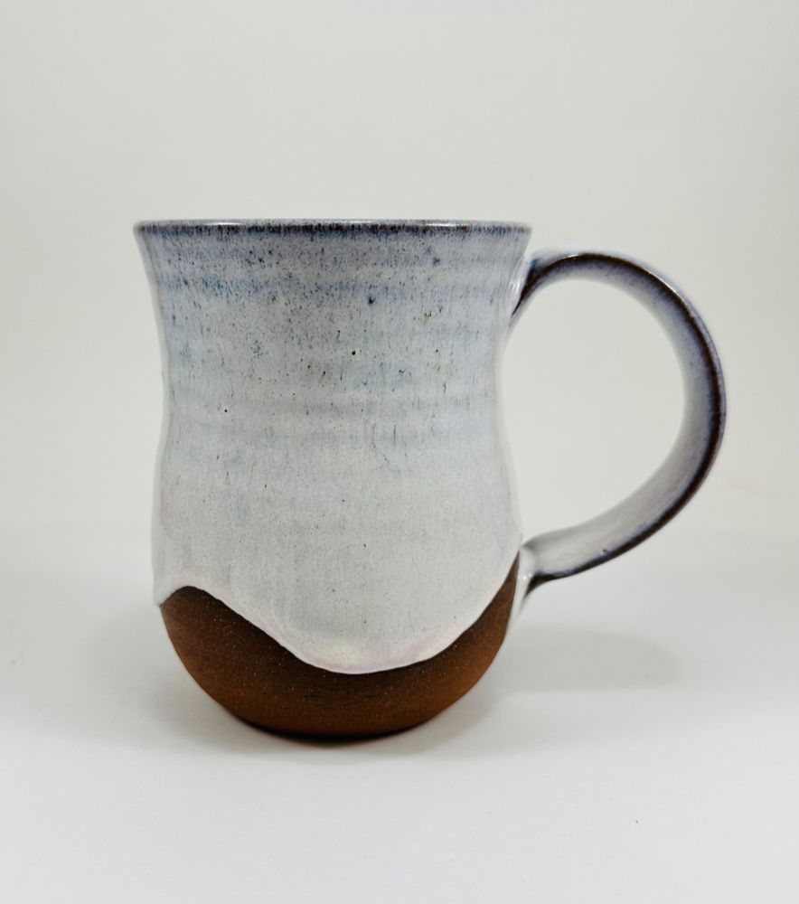 A handmade ceramic mug in a soft pink glaze. The mug is made from red clay 