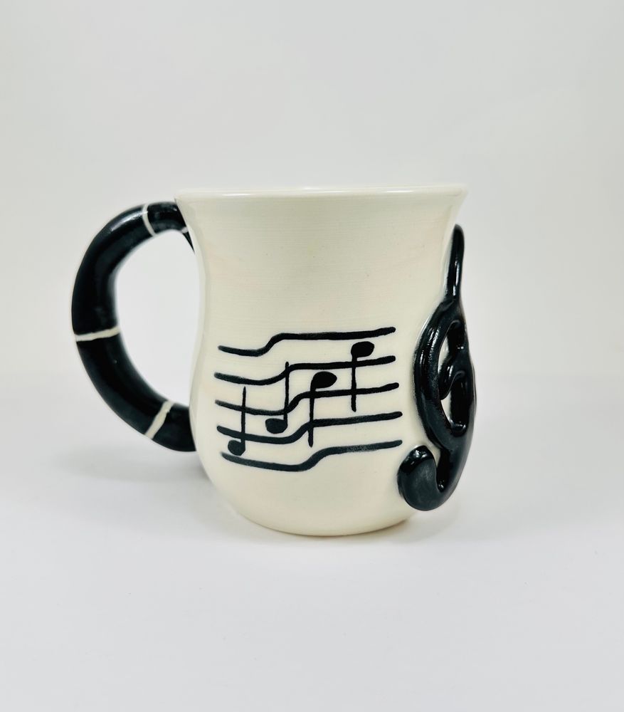 A handmade ceramic mug with a clarinet handle, music scale and treble clef