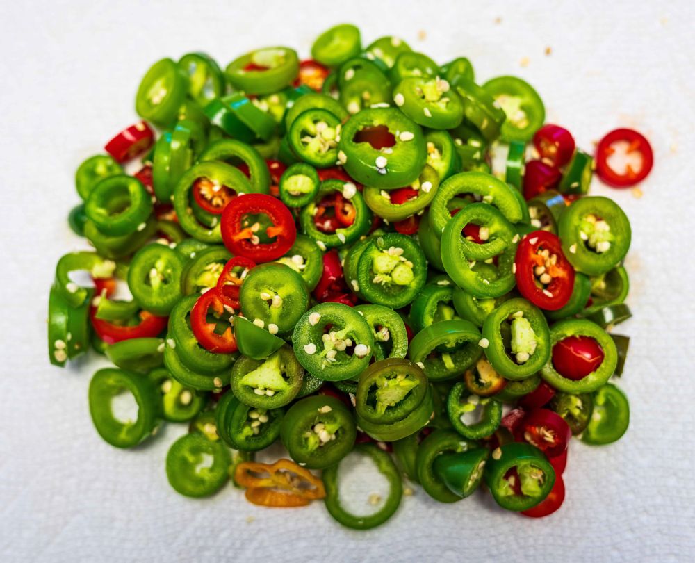 A mixture of green and red sliced chili peppers for pickling. 