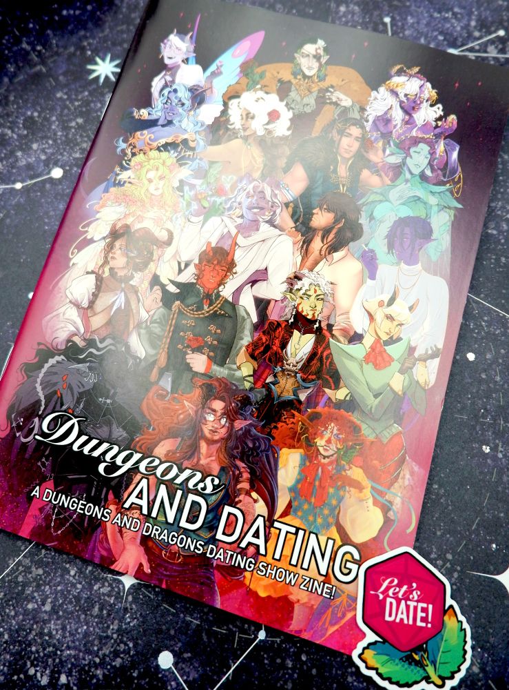 Photo of a zine called 'Dungeons & Dating', showing artwork of multiple D&D character designs on the front. Next to it is a sticker designed by Kroov saying 'Let's Date!' with a design of a rose shaped like a d20.