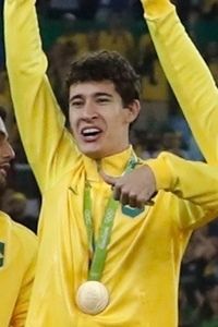 Volante Rodrigo Dourado comemorando a conquista da medalha de ouro no pódio olímpico.