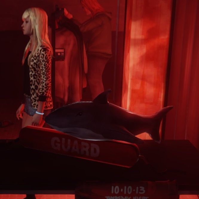 A stuffed gray and white shark plushie resting on a red lifeguard float with the word GUARD facing diagonally forward. 