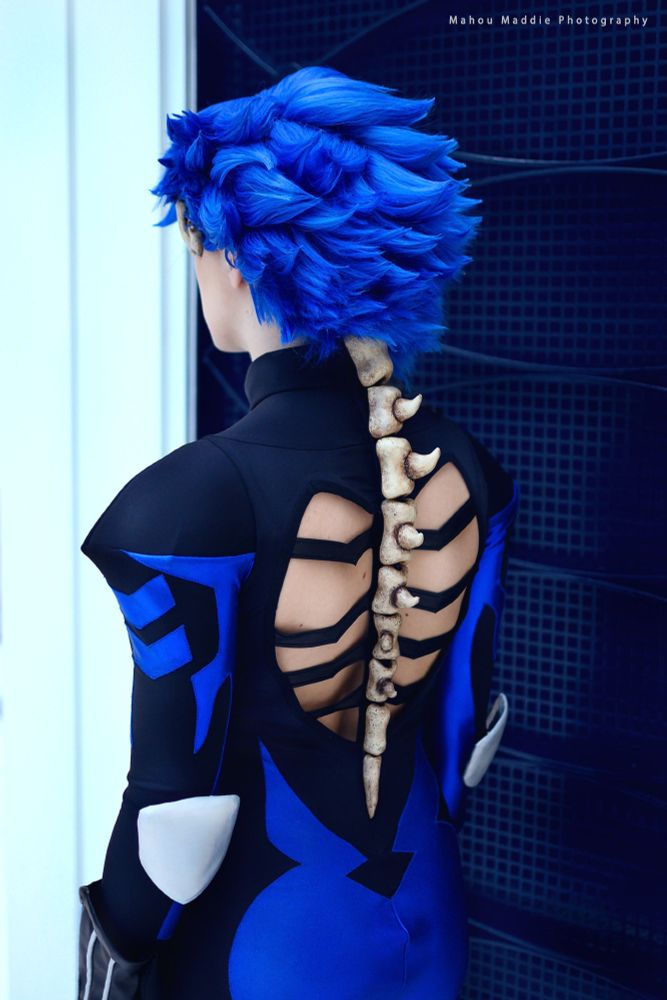 Cosplayer dressed in Adam's bone suit from sk8 the infinity, back toward the camera and showing off the back cutout and spine detail.