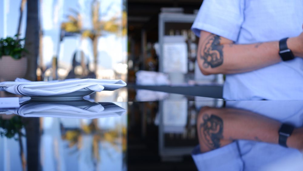 Light reflecting on glass with a mirror image of a man with a tattoo.