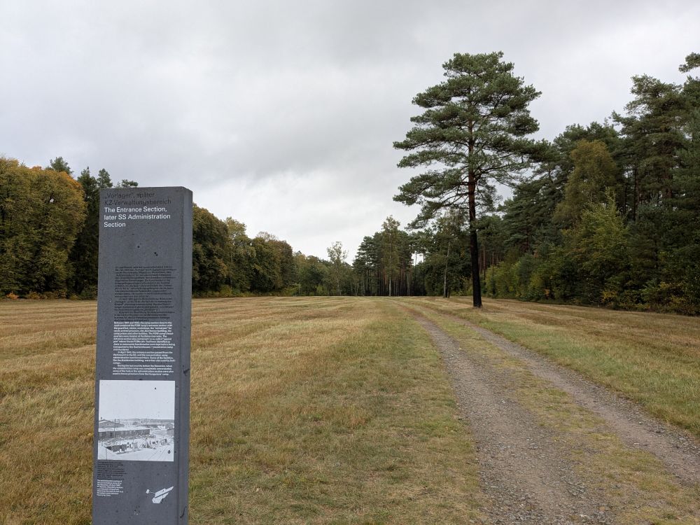 Blick über einen Teil der Außenanlagen der Gedenkstätte Bergen-Belsen mit Stele.
