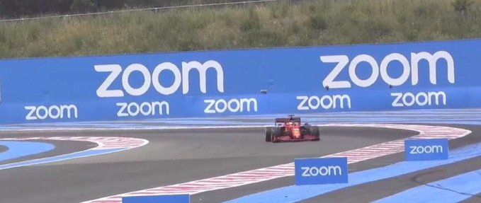 Racing car taking a corner with trackside banners for Zoom all over the place