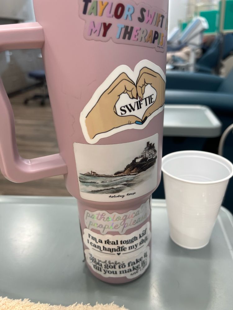 Tumbler with stickers all over it sitting on plastic gray tray