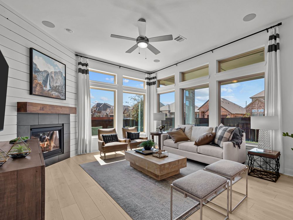 Spacious living room by David Weekley Homes with large windows showcasing mountain views, featuring a fireplace, modern furnishings, and a neutral color scheme.