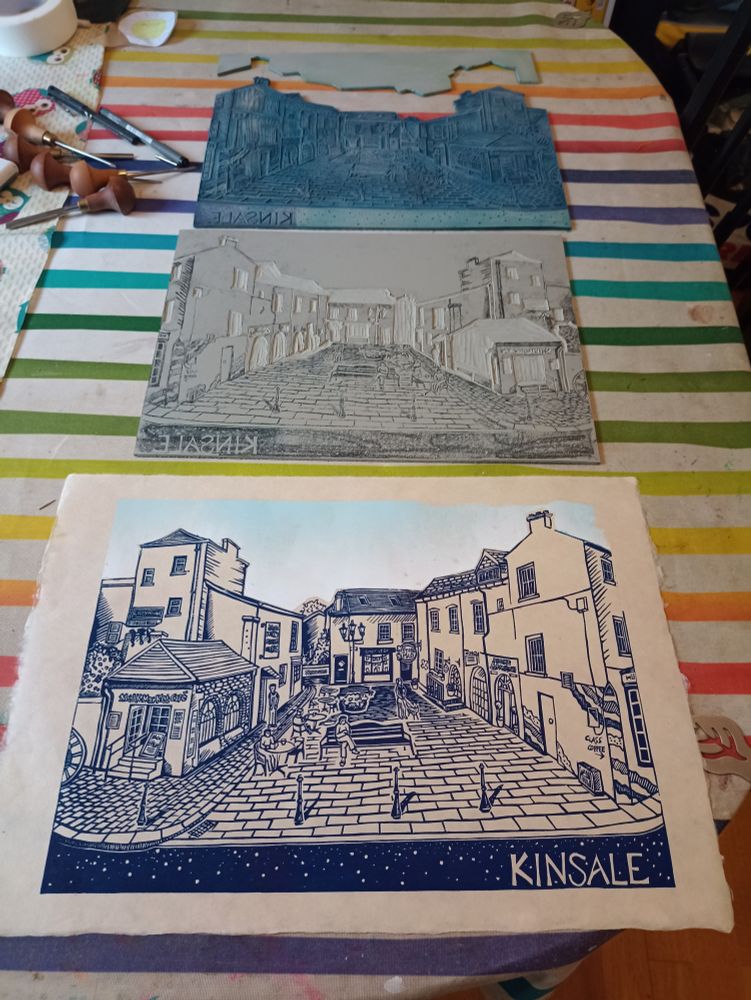 Linoprint of blue outlines of buildings in a square in Kinsale.  Also shows the lino blocks that will be used to create the colours of the buildings.