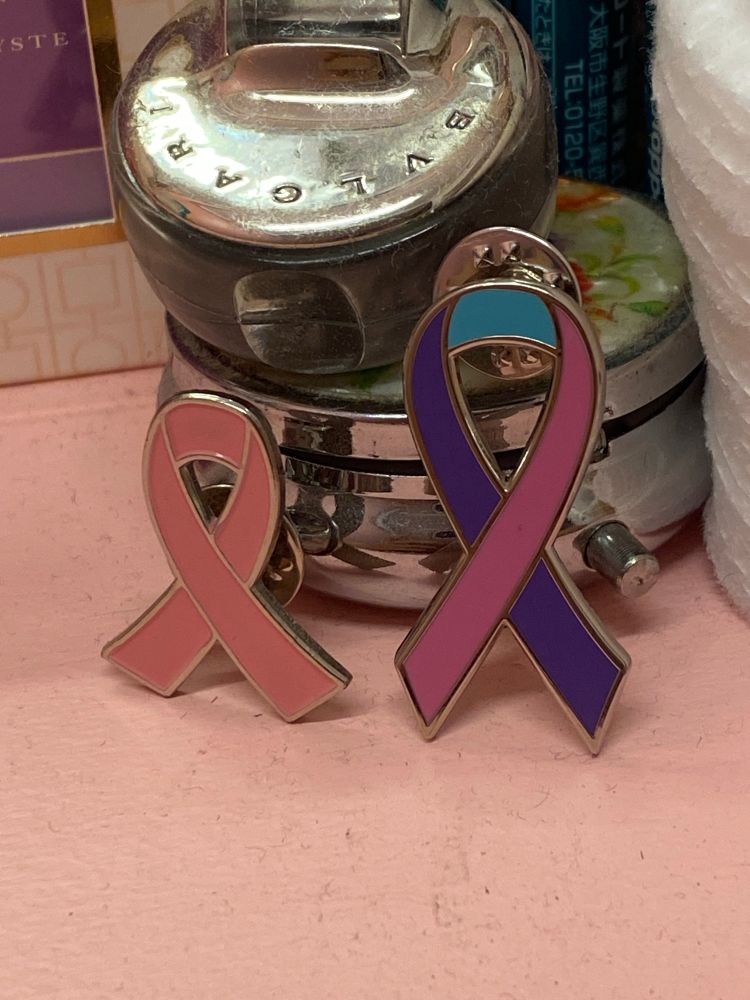 breast cancer and thyroid cancer ribbon pins beside each other in solidarity for all cancer patients battling these illnesses