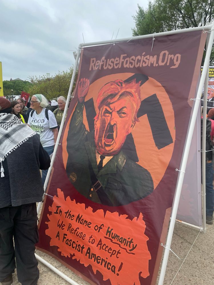 A poster depicting Trump with a Hitler mustache and a background swastika advertises RefuseFascism.org and states “in the name of humanity we refuse to accept a fascist America”