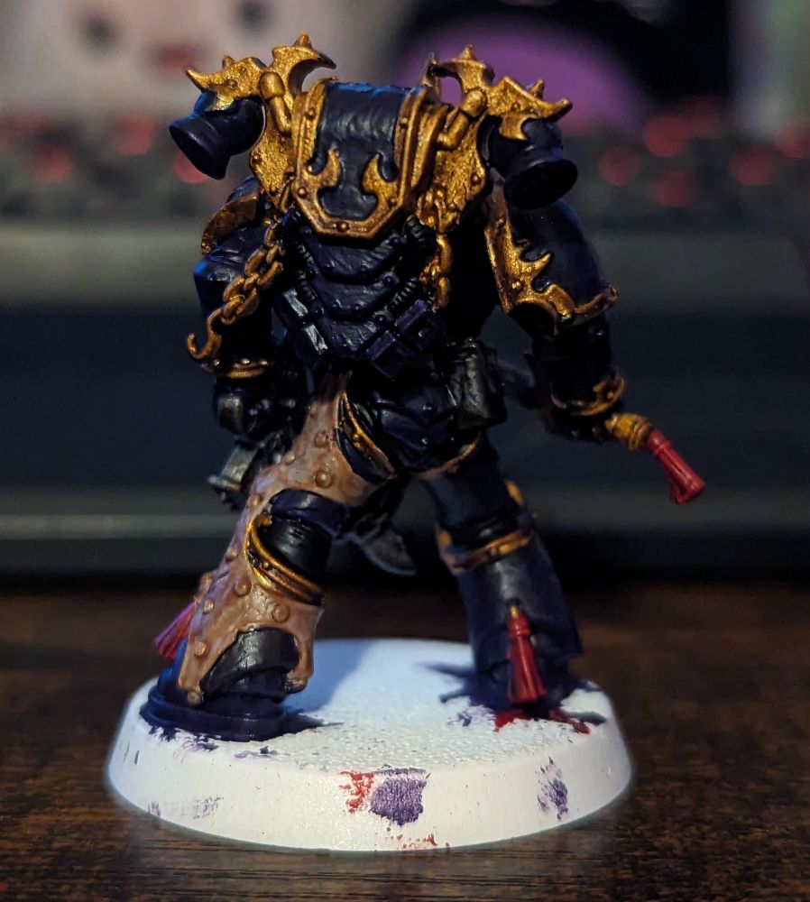 A Warhammer 40,000 miniature painted in purple and gold