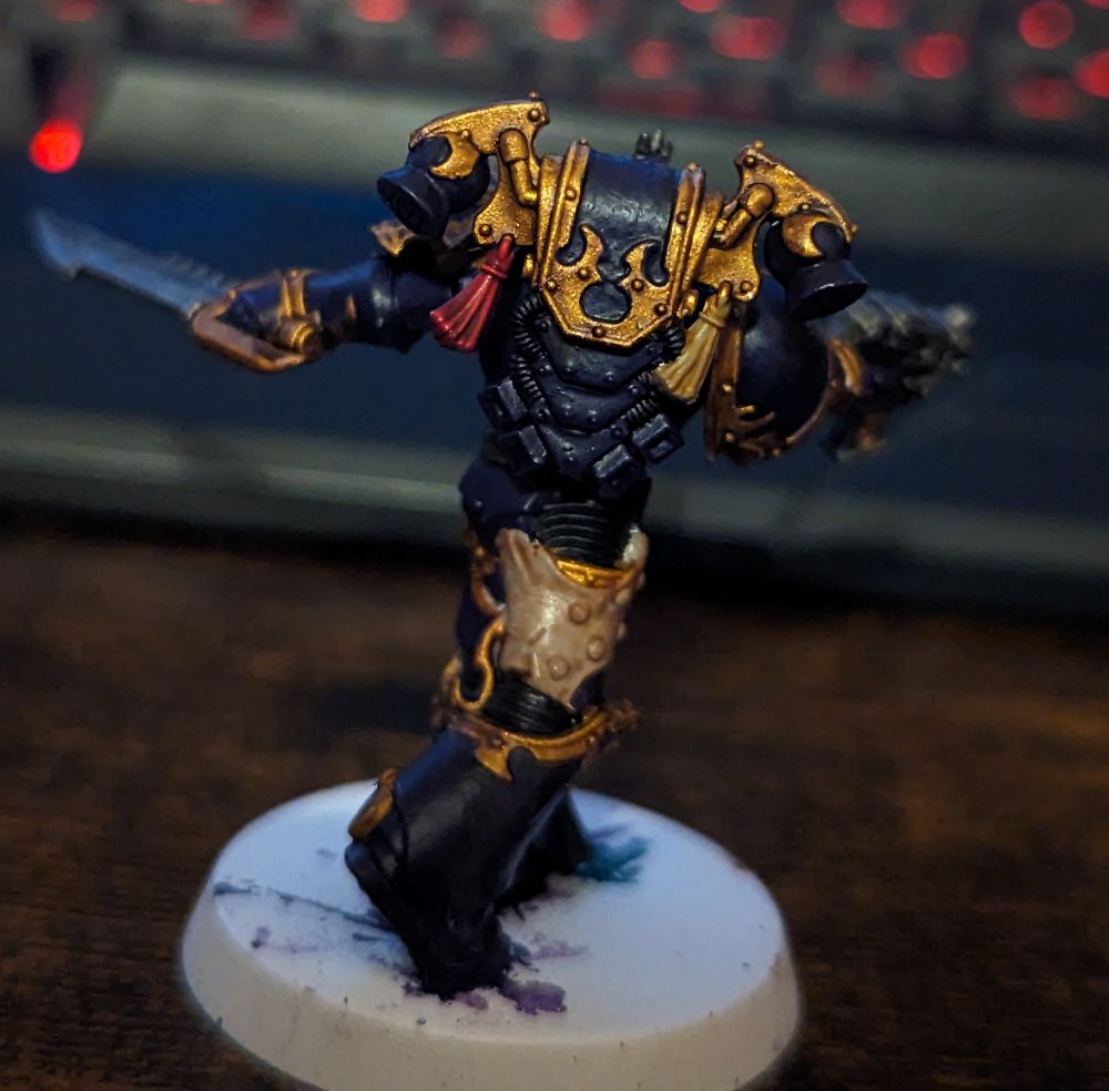 A purple and gold Warhammer 40,000 miniature