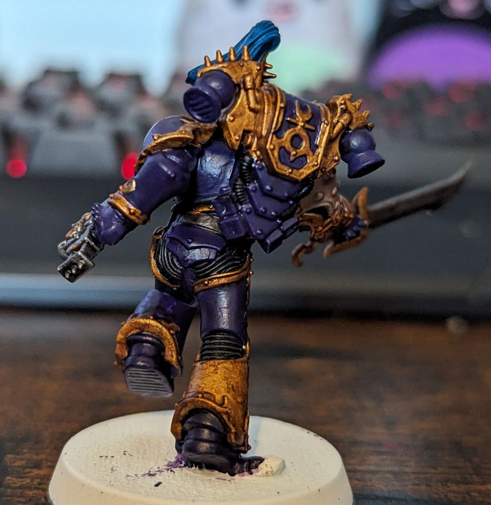 A Warhammer 40,000 miniature painted in purple and gold