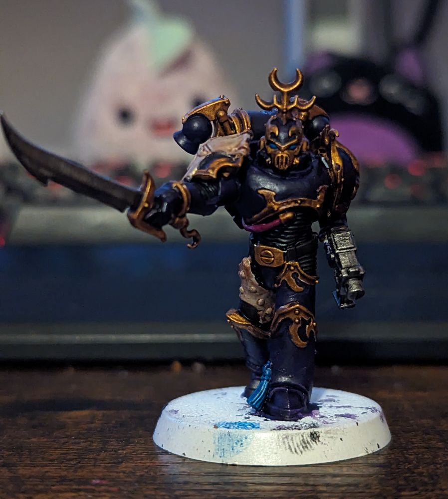 A Warhammer 40,000 miniature painted in purple and gold 
