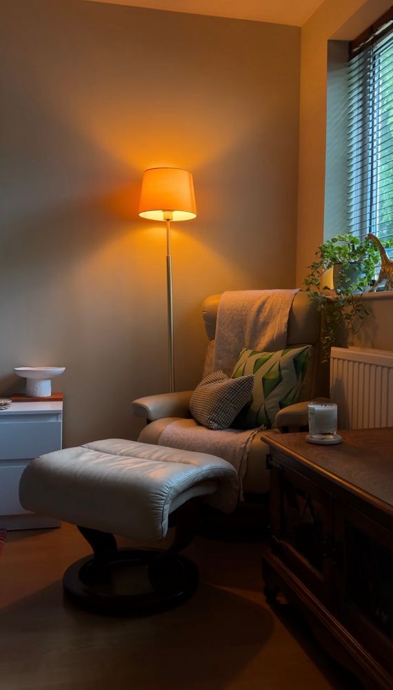 Cosy cream armchair next to a golden lamp