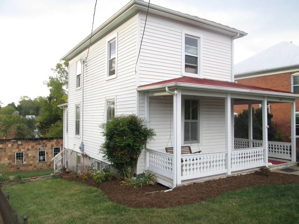 Row house, two story, white. Mulched garden bed, but no plants. 