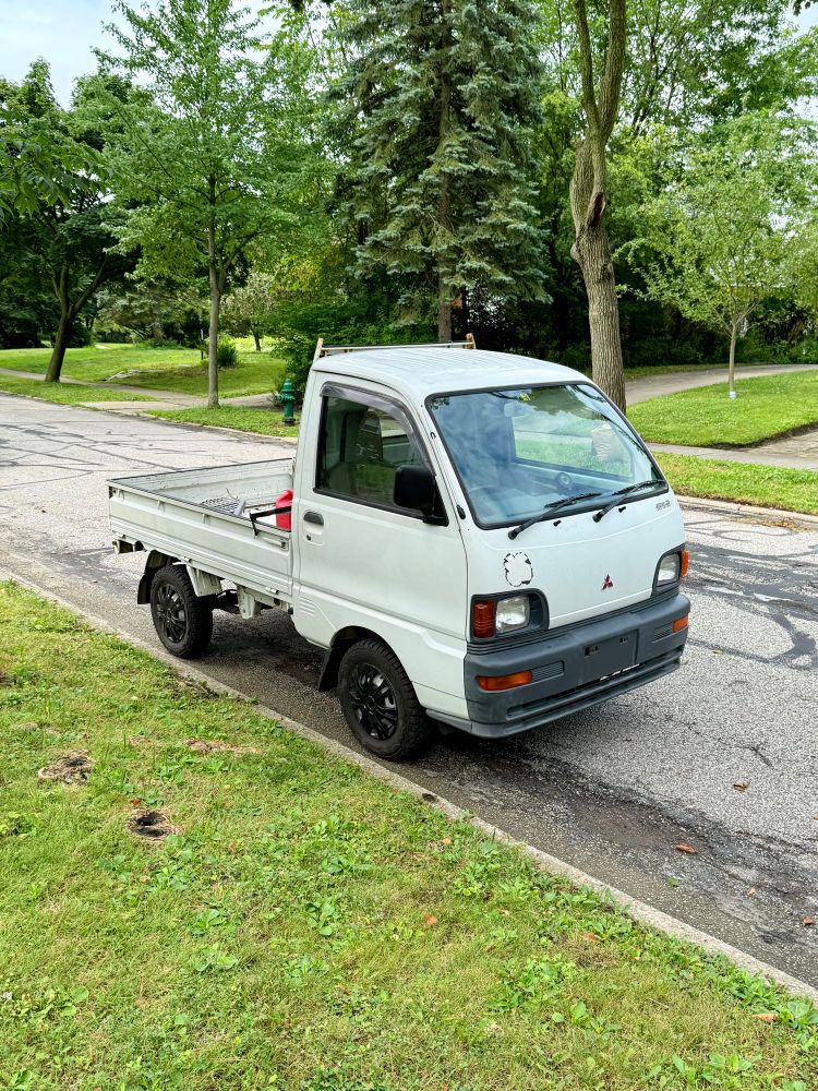 A white small work truck parked on a suburban street