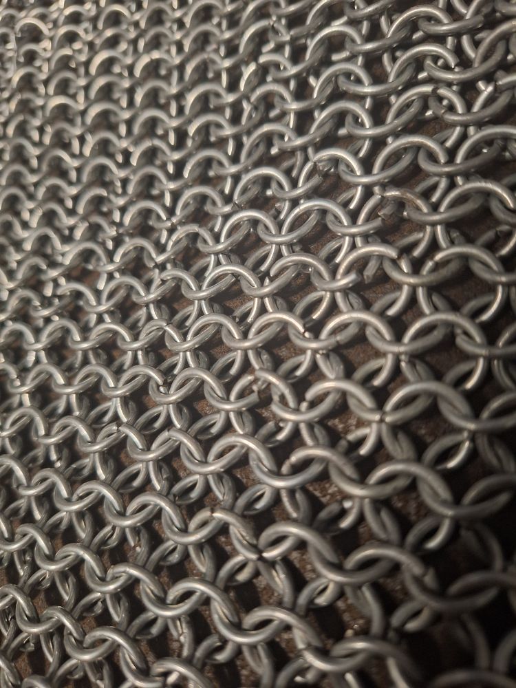 A close up on a chain mail sheet. No less than 100 metal hoops, interlocked with one another. 