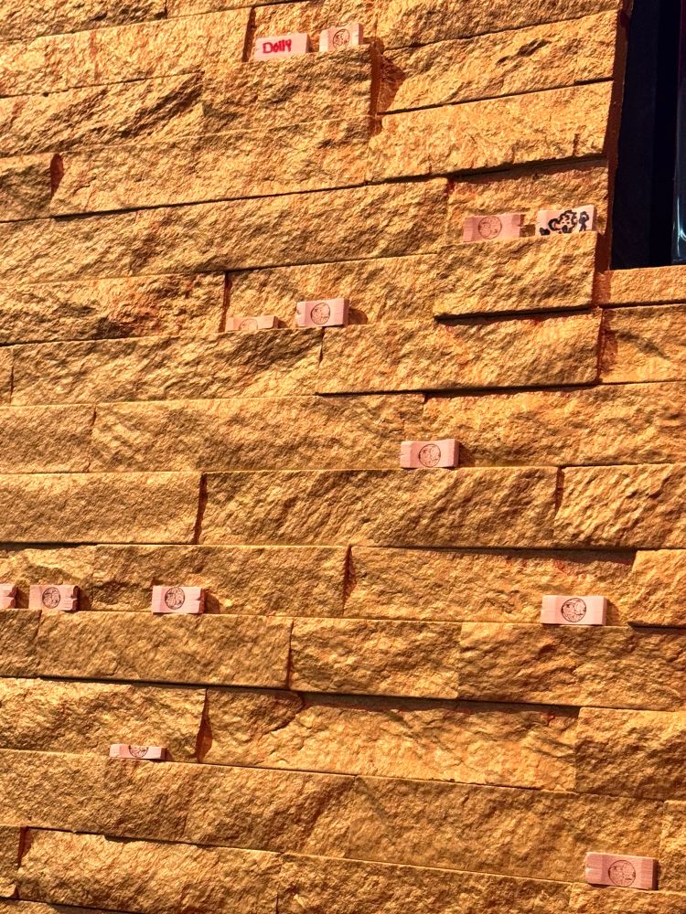 A photo of a golden wall with several wooden chopstick rests on it.
