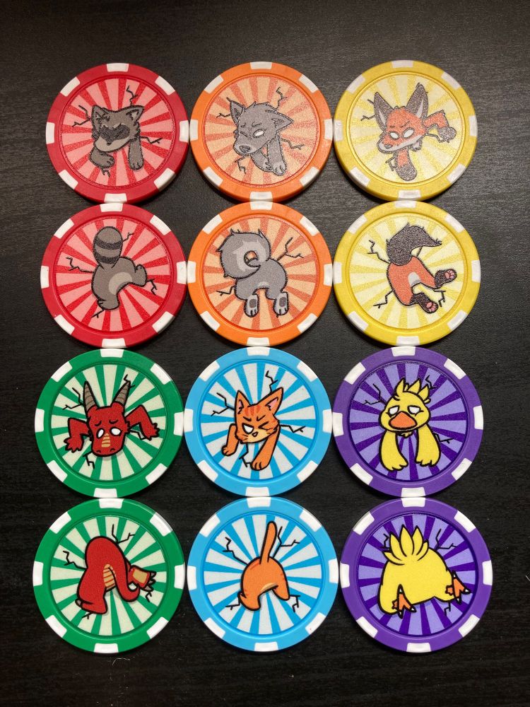 A photo of 12 poker chips with animals stuck inside them, one side with their face and the other side with their butt. There is a red chip with a raccoon, an orange chip with a wolf, a yellow chip with a fox, a green chip with a kobold/dragon, a light blue chip with a cat, and a purple chip with a fat chocobo.