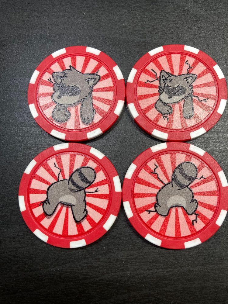 A photo of four red poker chips. They have a raccoon stuck in them, one side has the face and the other the butt. The designs on the left are a little bigger than the ones on the right.