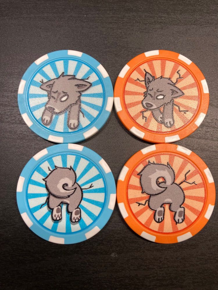 A photo of four poker chips, two light blue and two orange. They have a wolf stuck in them, one side has the face and the other the butt. The designs on the left are a little bigger than the ones on the right.