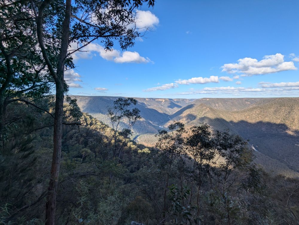 Clouds casting shadows across a green valley 