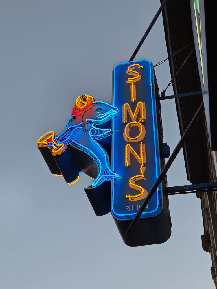 Neon sign for Simon's with a viking fish holding a cocktail glass 