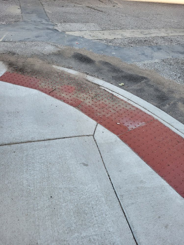 A curb cut out with a lot of debris, observed as part of a walk audit