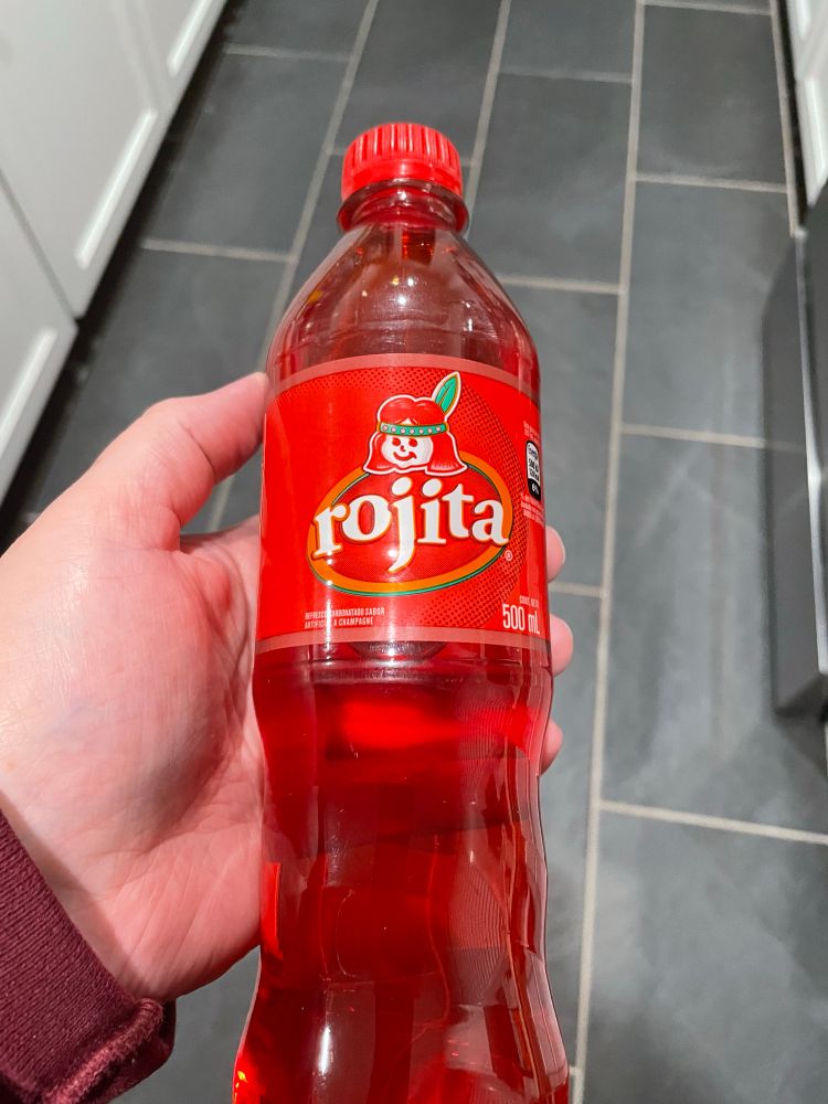 Me holding a bottle of rojita soda. It is a glowing red color.