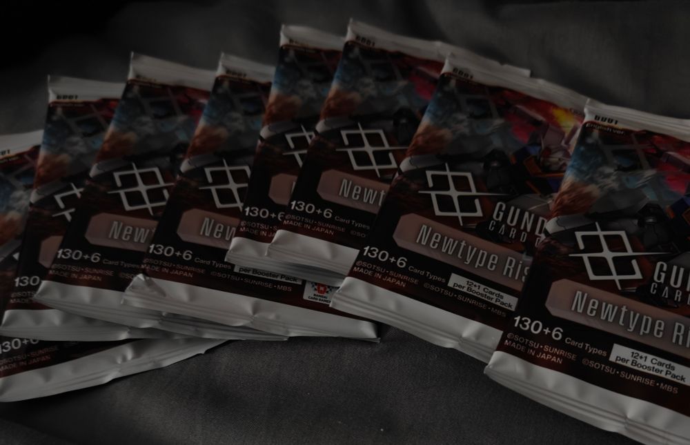 8 packs of Gundam card game packs they're white with pink blue and white on them it says new type rising 