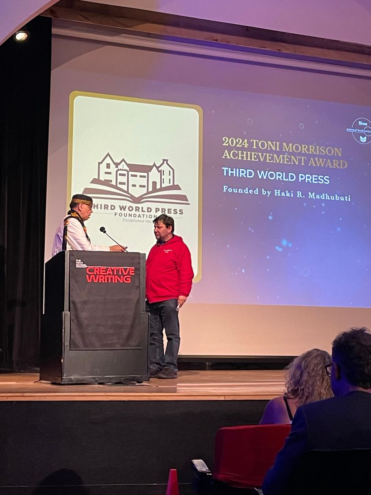 Dr. Madhubuti and Jacob Appel in front of a screen that reads: 2024 Toni Morrison Achievement Award THIRD WORLD PRESS Founded by Haki R. Madhubuti.