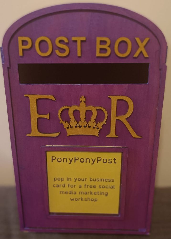 It's a purple post box with gold lettering. It's painted with enthusiasm, if not skill. 